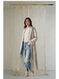 Celeni light beige oversized coat with fringe detail, notch lapels, and buttoned cross closure. Made from recycled polyester, wool, and cotton.